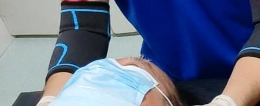 Practitioner in SIFU TIT TAR uniform performing a head and neck treatment in Singapore